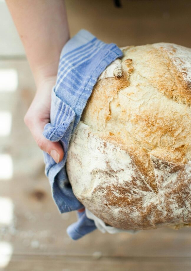 Hand holding a loaf of homemade bread